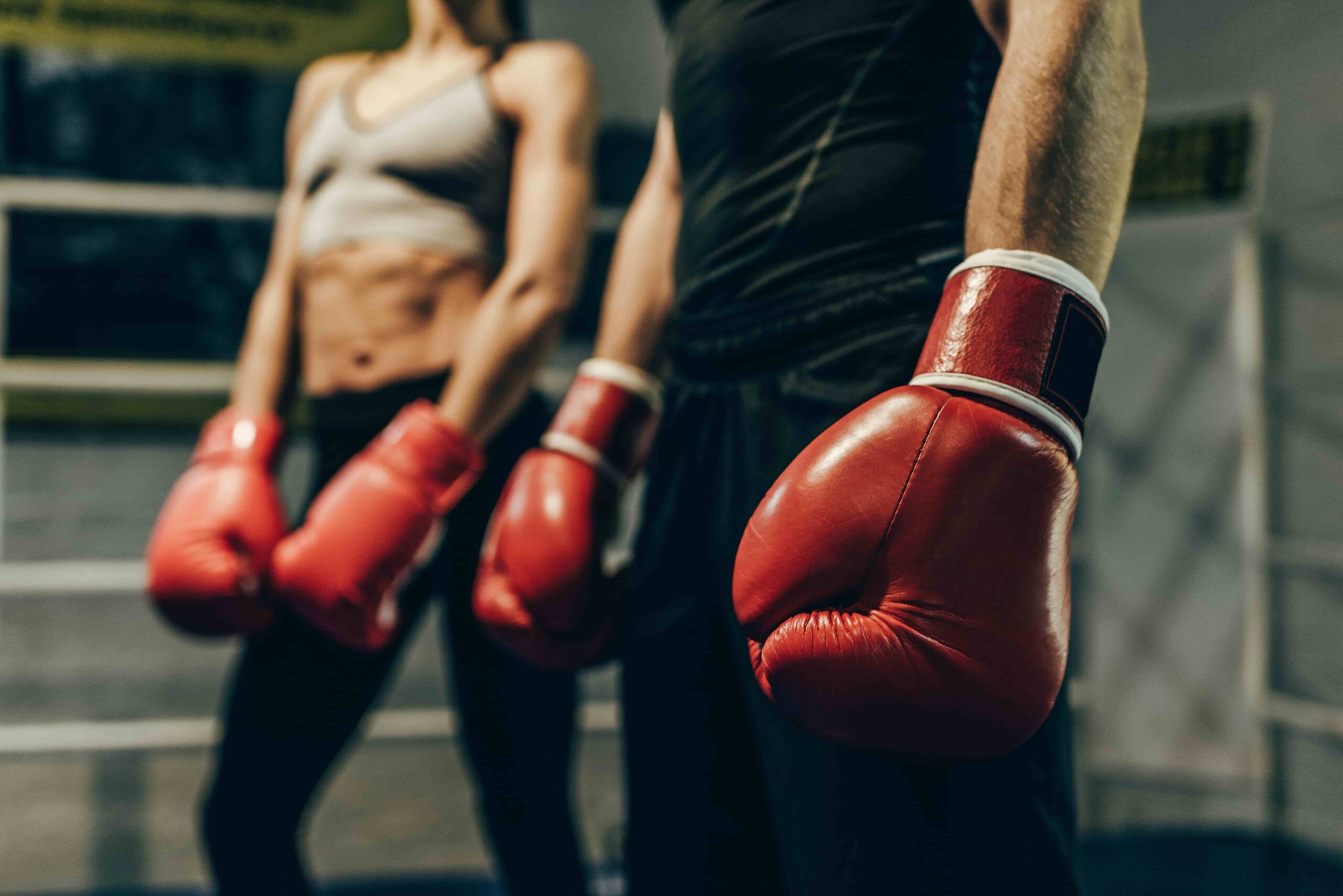 Benefits of boxing and combat training, man and woman wearing boxing gear.