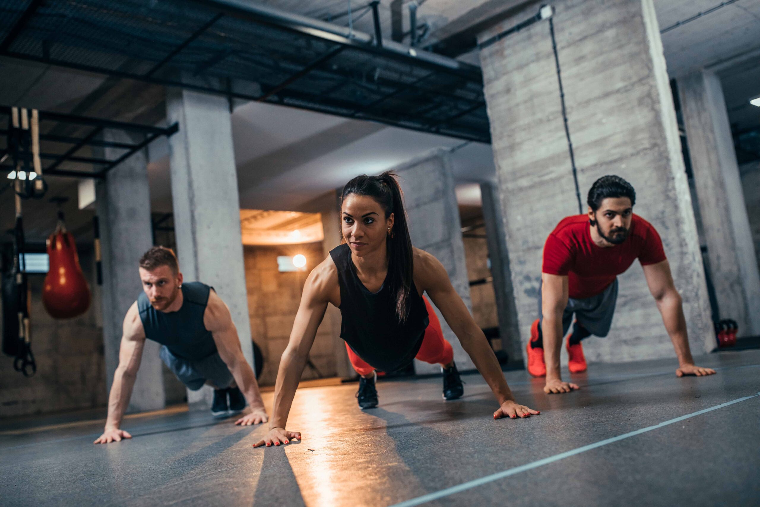HIIT vs Circuit Training, a woman and two men doing push-ups.