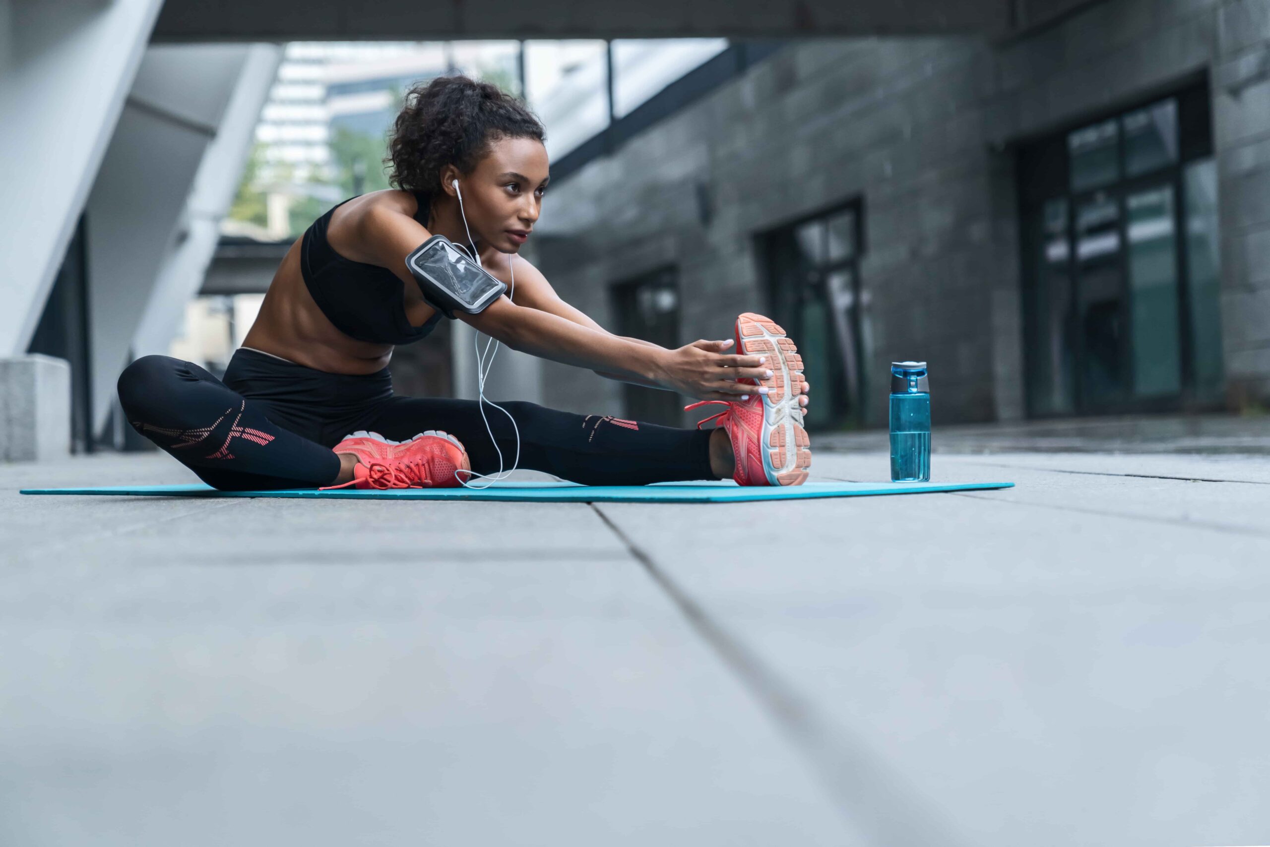 Fitness motivation, woman stretching on a yoga mat outdoors.